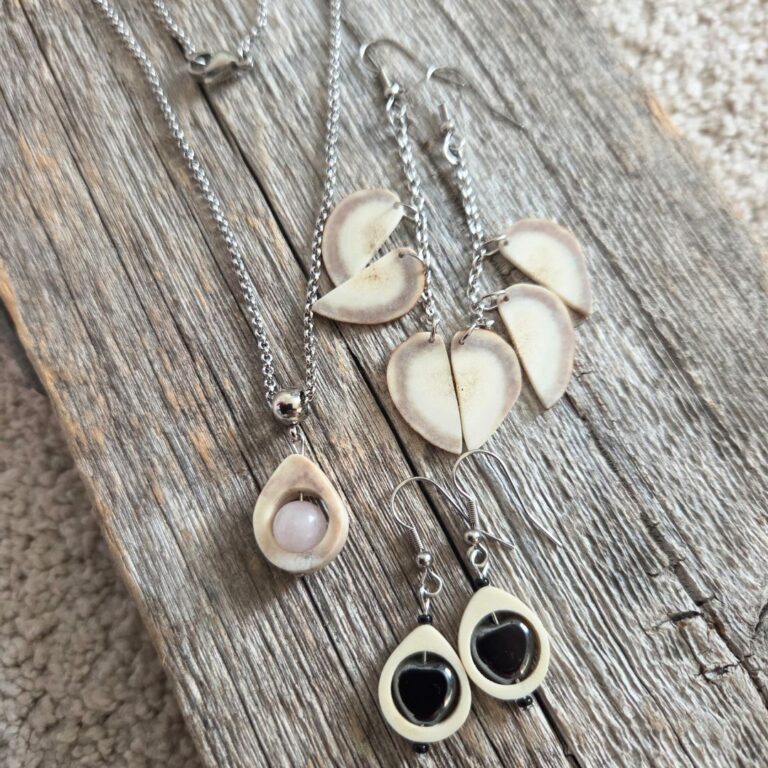 käsintehtyjä, poronsarvesta tehtyjä koruja vanhan laudan päällä.